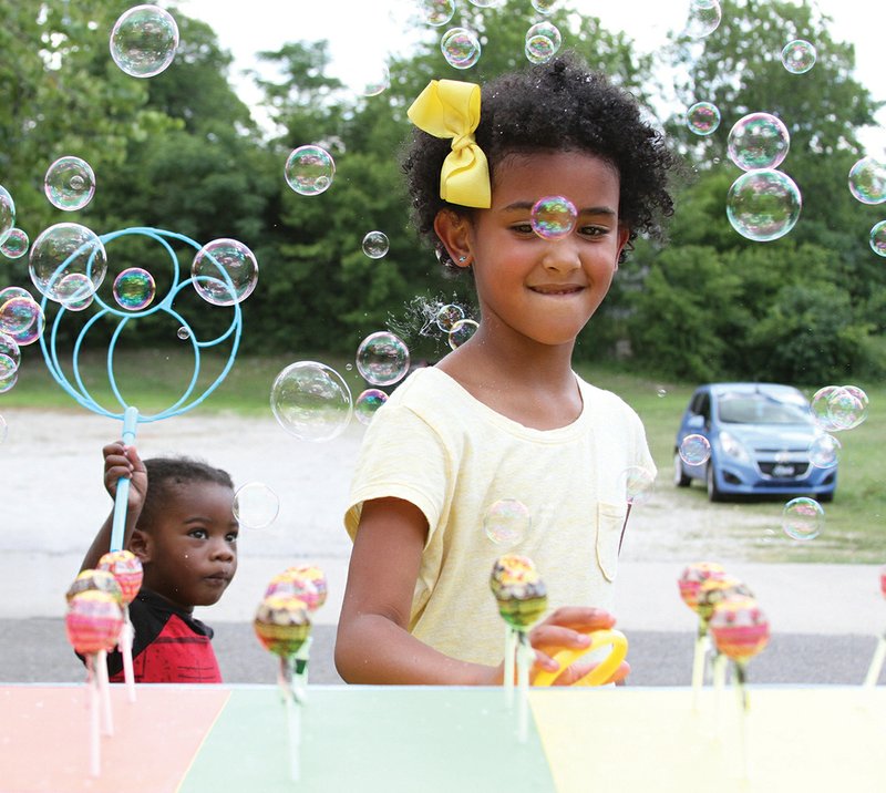 Leae Dejesus, 7 year-old of Hot Springs, attempts a ring-toss during a Juneteenth Celebration on Gulpha Street, Saturday June 16. (The Sentinel-Record/Rebekah Hedges)