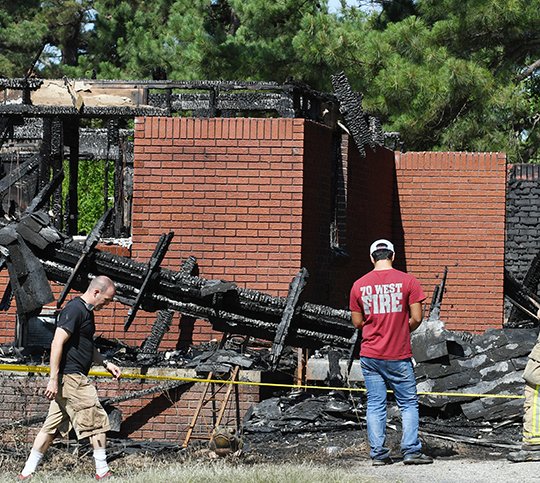 The Sentinel-Record/Grace Brown - Members of the 70 West Fire Department look over the remnants of the house at 298 Pittman Road after a house fire broke out around 4 a.m. on Sunday, June 17, 2018. 