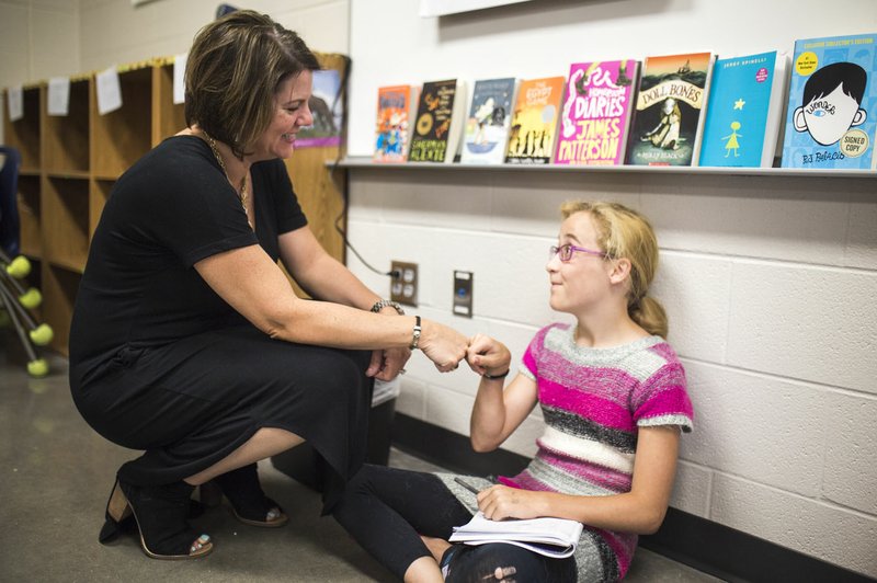 NWA Democrat-Gazette/CHARLIE KAIJO Creekside Middle School Literacy Facilitator Christin Rupert (from left) fist bumps Bethany Crose, 11, during a summer writing camp Thursday at Creekside Middle School in Bentonville. Fifth-graders at Creekside Middle School learned about writing strategies and the writing process in a two-week summer writing camp. The camp was hosted by Creekside Middle School with the University of Arkansas and The National Writing Project.