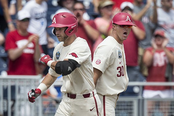 Nate Thompson, Arkansas assistant coach, congratulates Luke Bonfield as he rounds thrid after hitting a two-run homer in the 5th inning vs Texas Sunday, June 17, 2018, during game three of the NCAA Men's College World Series at TD Ameritrade Park in Omaha.