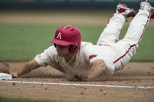 Arkansas' Jared Gates slides into third base during a College World Series game against Texas on Sunday, June 17, 2018, in Omaha, Neb. 
