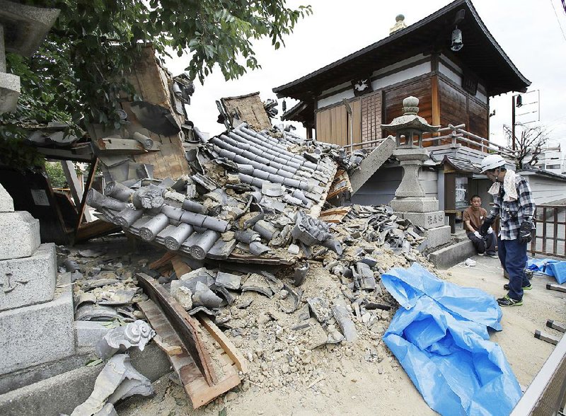 The gate of Myotoku-ji temple collapses after an earthquake hit Ibaraki City, Osaka, western Japan, on Monday. 
