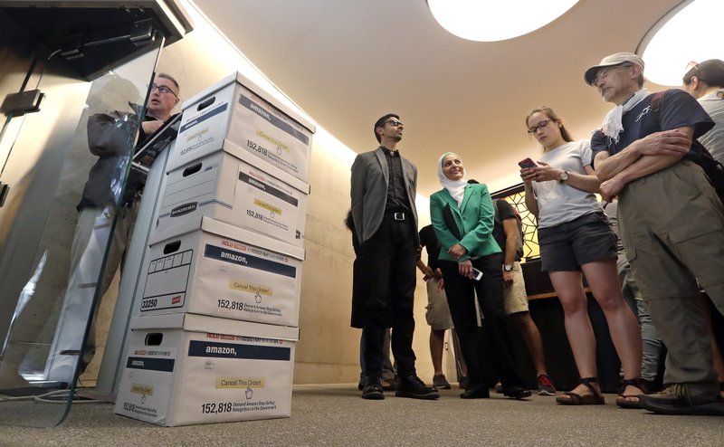 Shankar Narayan, legislative director of the ACLU of Washington, center, stands with Aneelah Afzali, of the Muslim Association of Puget Sound (MAPS) and others as they wait to deliver petitions at Amazon headquarters, Monday, June 18, 2018, in Seattle. Representatives of community-based organizations urged Amazon to stop selling its face surveillance system, Rekognition, to the government. They later delivered the petitions to Amazon supporting the call for the company to not sell the mass surveillance system to government. (AP Photo/Elaine Thompson)