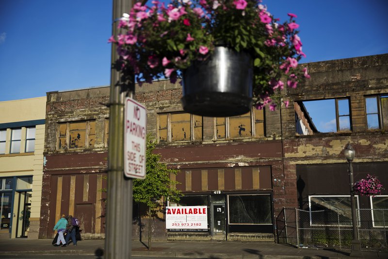 In this June 2017 file photo, dilapidated storefronts stand along baskets of pink petunias that hang from light posts all over town, watered regularly by residents trying to make their city feel alive again in Aberdeen, Wash. From drivers paying more for gas and families bearing heavier child care costs to workers still awaiting decent pay raises to couples struggling to afford a home, people throughout the economy are straining to succeed despite the economy’s gains. (AP Photo/David Goldman, File)