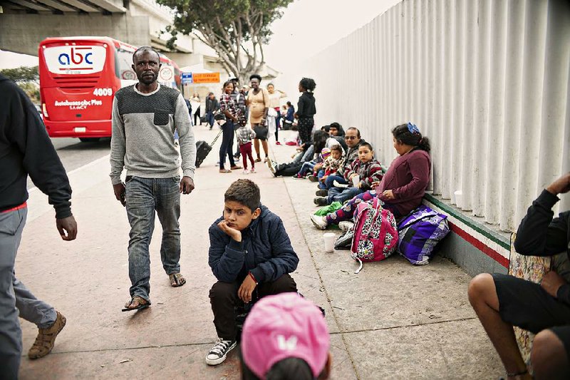 People wait for asylum hearings Tuesday outside the U.S. port of entry in Tijuana, Mexico, as U.S. officials considered changes in immigration law.