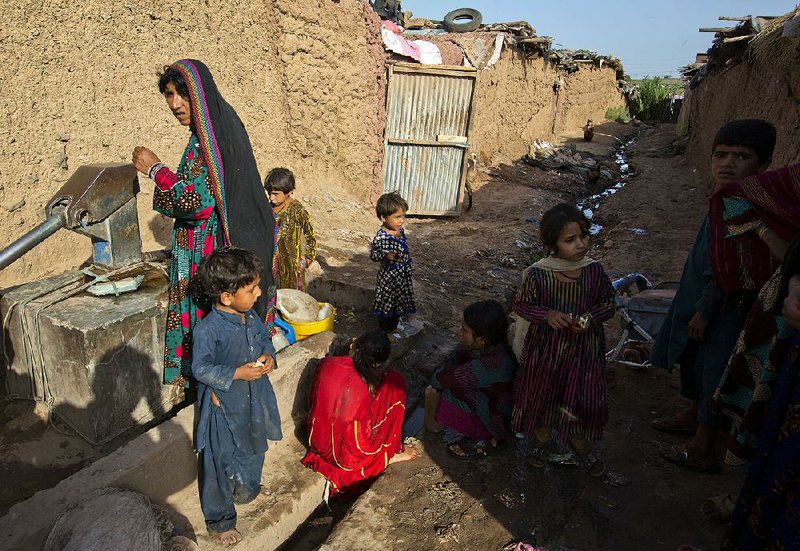 Refugees from Afghanistan fetch water Tuesday near their mud houses in a suburb of Islamabad, Pakistan. According to a United Nations report released Tuesday, Afghanistan was among the countries with the most displaced people.