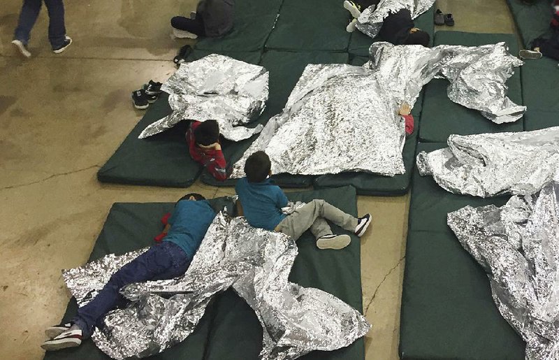 In this photo provided by U.S. Customs and Border Protection, youths rest in one of the cages at a center in McAllen, Texas, near the three “tender age” centers where babies and young children separated from their parents are being held.  