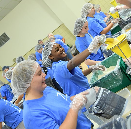 The Sentinel-Record/Grace Brown PACK IT UP: Grace Rooney, left, of Guy, and Halli Lemons, of Newport, work to pack 30,000 meals with other members of the Arkansas Future Farmers of America Wednesday at Camp Couchdale.