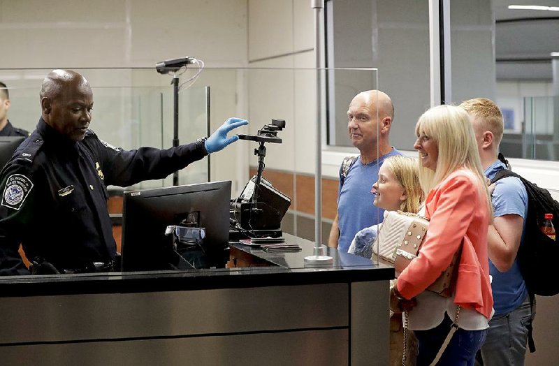 A U.S. Customs agent screens a family with face recognition software Thursday at Orlando International Airport. 