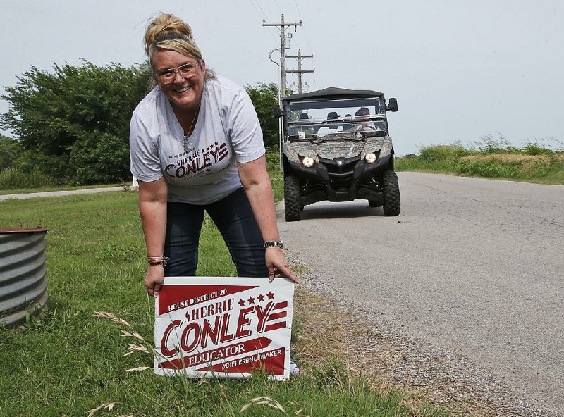 Elementary school principal Sherrie Conley, who is running for state representative in District 20, plants a campaign sign along a road in Goldsby, Okla.  