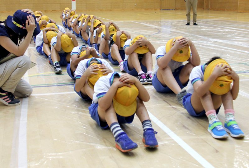 In this July 14, 2017, photo, elementary school students participate in an evacuation drill in Takaoka, Toyama prefecture, northwest of Tokyo, following repeated missile launches by North Korea. Cabinet Secretariat in charge of crisis management said Thursday, June 21, 2018, Japan plans to suspend civilian evacuation drills planned for the rest of the year amid easing tension following the U.S.-North Korea summit. (Kyodo News via AP)