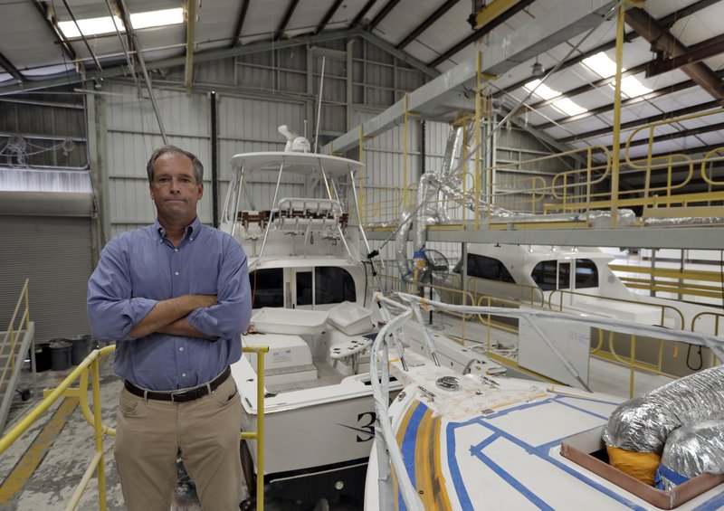 Peter Truslow, chief executive officer for Bertram, a boat building company, poses near three of his custom made boats Friday in Tampa, Fla. (AP Photo/Chris O'Meara)