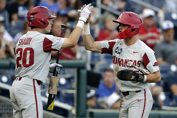 Arkansas' Casey Martin, right, high-fives teammate Carson Shaddy (20) after scoring against Florida on an RBI-single in the first inning of an NCAA College World Series baseball game in Omaha, Neb., Friday, June 22, 2018. (AP Photo/Nati Harnik)

