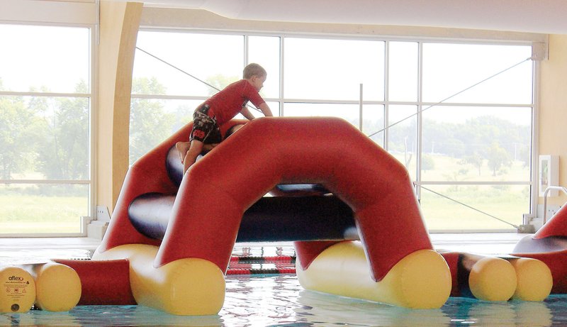 Ethan Orsburn, 7, of Russellville moves carefully through the inflatable obstacle course at the Russellville Aquatic Center. The $6.6 million facility opened a year ago on June 28 and has added programming and activities since then. The obstacle course was purchased this summer.