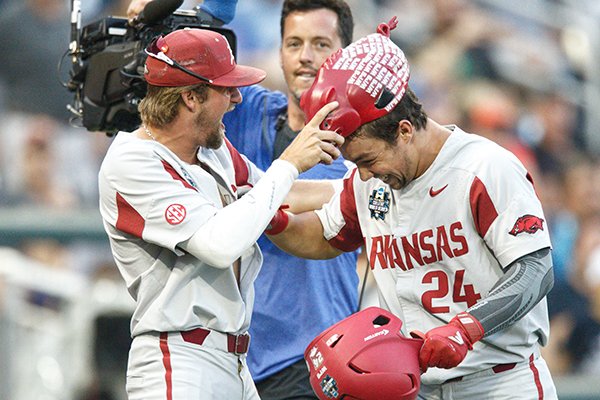 Arkansas infielder Hunter Wilson, left, places a Hog hat on outfielder Dominic Fletcher after Fletcher hit a home run during a College World Series game against Florida on Friday, June 22, 2018, in Omaha, Neb.