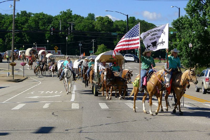 Wagons and horses of the Harrison Roundup Club pass through downtown Harrison on Friday morning on their way to Springdale. 