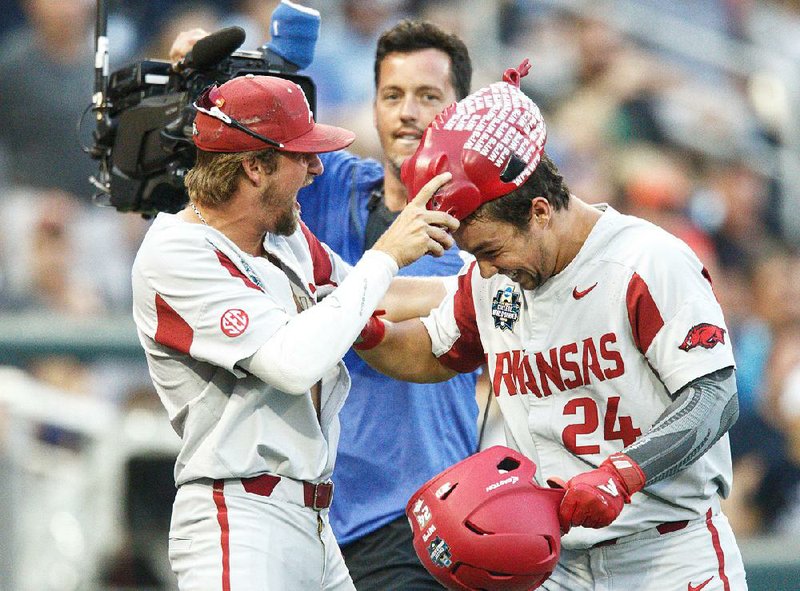 Arkansas’ Dominic Fletcher (right) is presented the home run hog hat by Hunter Wilson after he hit a home run in the Razorbacks’ victory over Florida on Friday night at the College World Series. The Hogs open play in the best-of-three championship series Monday. 