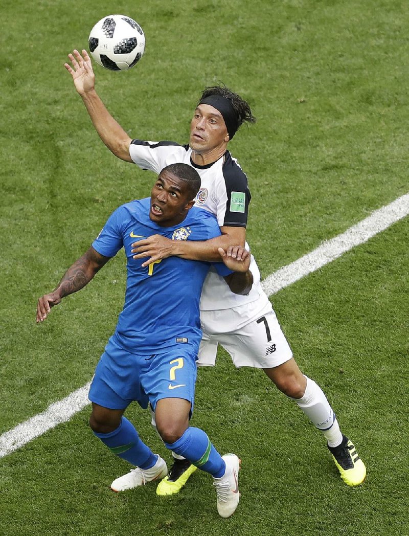 Costa Rica’s Christian Bolanos (right) challenges for the ball with Brazil’s Douglas Costa in Brazil’s 2-0 victory Friday. The victory allows Brazil to advance into the knockout stage of the World Cup. 