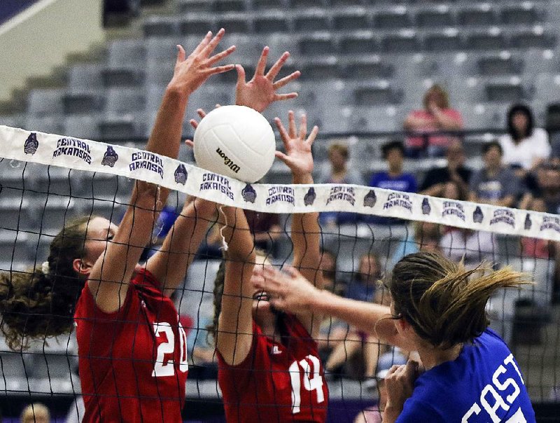 Kelsey Moody (5) for the East gets her spike blocked by the West’s Caitlin Murdock (20) and Emma Palasak (14) during the Arkansas High School Coaches Association All-Star volleyball game Friday at the Ferris Center in Conway. 