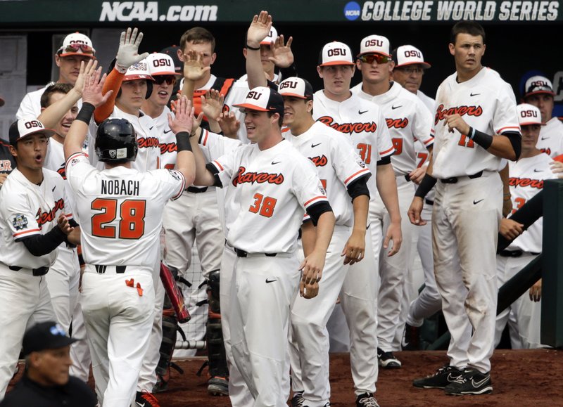 Oregon State's Kyle Nobach (28) is greeted at the dugout after he scored against Mississippi State on a one-run single by Michael Gretler in the second inning of an NCAA College World Series baseball game in Omaha, Neb., Friday, June 22, 2018. (AP Photo/Nati Harnik)