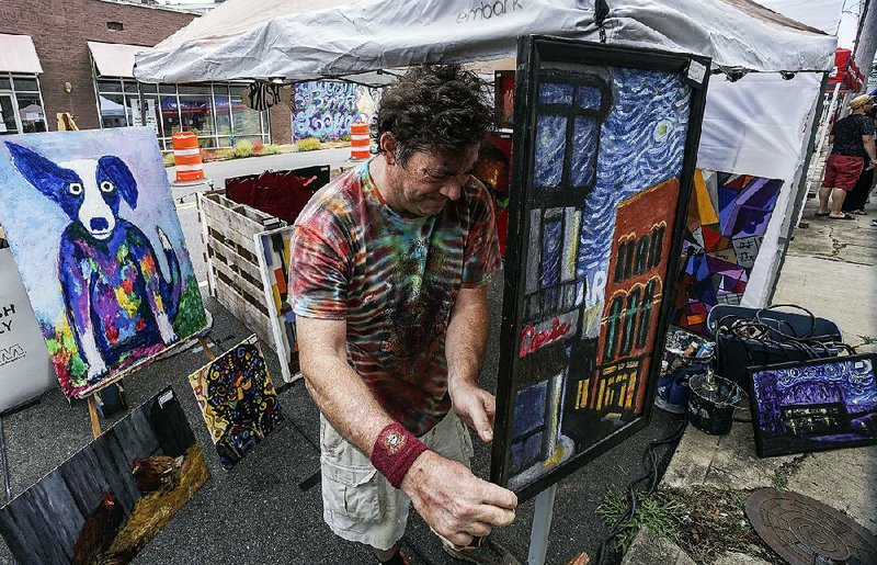 Jason Harper of Little Rock hangs his work Saturday during the PopUp in the Rock event in the capital city’s Stifft Station neighborhood. 
