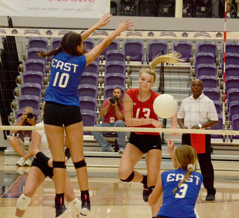 Graham Thomas/Siloam Sunday West hitter Shaylon Sharp of Siloam Springs, No. 13, hits the ball past the East defense of Mikayla Kirk of Pocahontas, No. 10, and Aryn Blumenberg of Conway during the first set of Friday's Arkansas High School Coaches Association All-Star Volleyball Match at the Farris Center on the campus of the University of Central Arkansas in Conway.