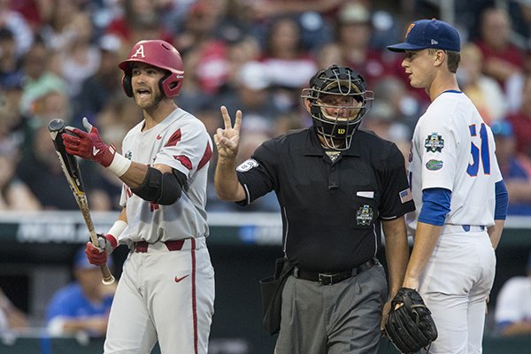 Arkansas designated hitter Luke Bonfield, left, contends he was interfered with while home plate umpire Travis Katzenmeier, center, and Florida pitcher Brady Singer look on during a College World Series game Friday, June 22, 2018, in Omaha, Neb.