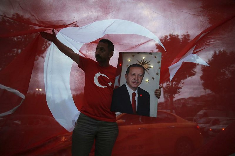 A man holds a picture of Recep Tayyip Erdogan, Turkey’s president and ruling Justice and Development Party leader, while celebrating outside the party headquarters Sunday in Istanbul.  
