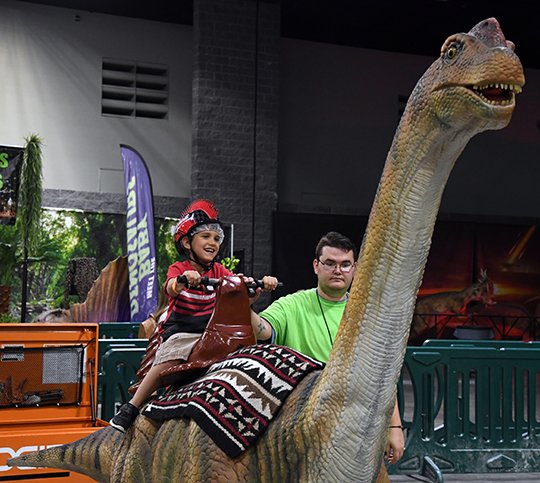 The Sentinel-Record/Grace Brown- Cristofer Valle, 6, of Texarkana enjoys a ride on a brontosaurus at the Jurrasic Quest exhibit on display at the Hot Springs Convention Center on Sunday, June 24, 2018. 