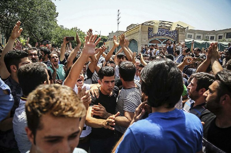 Iranians rally Monday at the main gate of Tehran’s historic grand bazaar, forcing shops to close, while protesting the Islamic Republic’s troubled economy. 