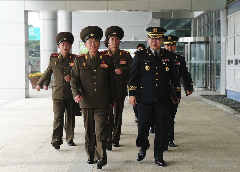In this photo provided by South Korea Defense Ministry, North Korean army Col. Om Chang Nam (front left) walks with his South Korean counterpart Col. Cho Yong-geun (front right) to hold a meeting at the Customs, Immigration, and Quarantine office in Paju, South Korea, on Monday.  