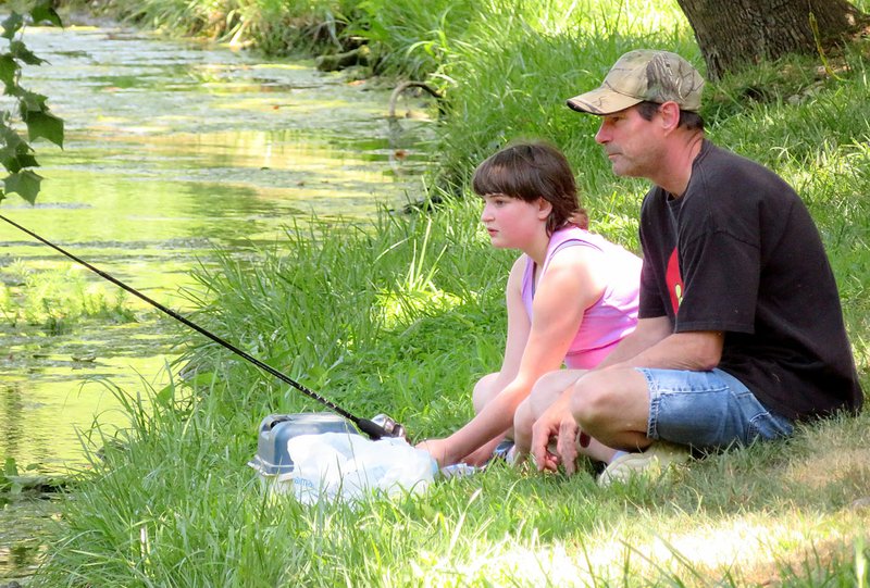 Westside Eagle Observer/RANDY MOLL Aleisha Boyd, 11, with her father, Charley Boyd, enjoyed an afternoon of fishing together on Saturday, June 23, 2018, at the Flint Creek Nature Park in Gentry while participating in the annual fishing derby sponsored by the Gentry Chamber of Commerce.