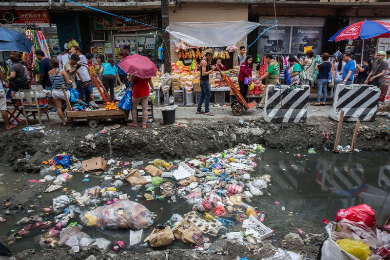 Trash lies in a gutter as customers shop at Quiapo Market in Manila, the Philippines, on Feb. 2, 2017. MUST CREDIT: Taylor Weidman/Bloomberg