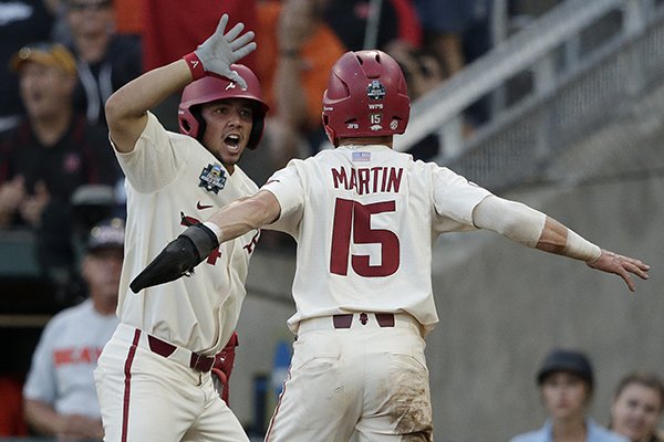 Arkansas' Casey Martin (15) is congratulated by Dominic Fletcher after scoring a run against Oregon State during the fifth inning of Game 2 of the NCAA College World Series baseball finals in Omaha, Neb., Wednesday, June 27, 2018. (AP Photo/Nati Harnik)

