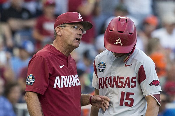 Arkansas coach Dave Van Horn, left, talks with third baseman Casey Martin during a College World Series finals game Tuesday, June 26, 2018, in Omaha, Neb.