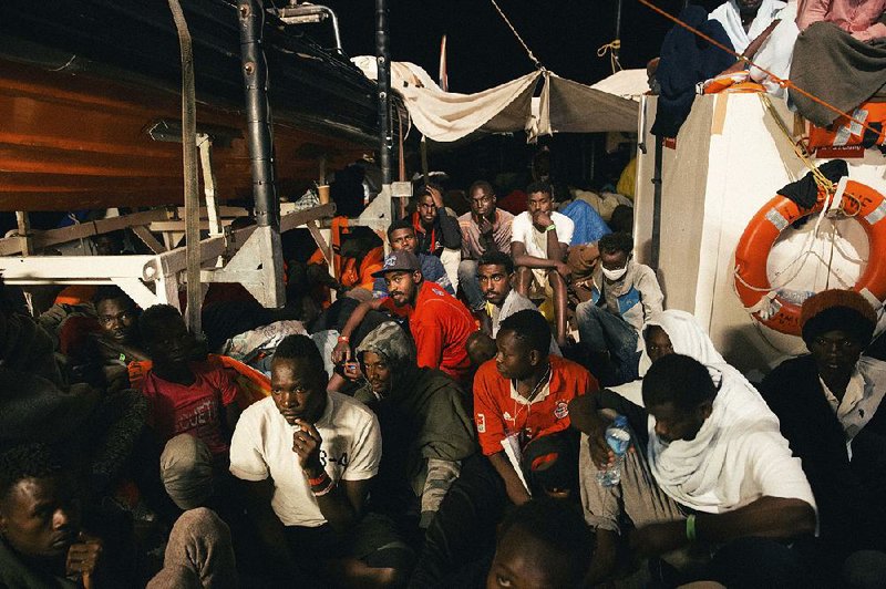 Rescued migrants wait in the search-and-rescue ship of German aid group Mission Lifeline as the boat remained stranded off Malta early Monday.  