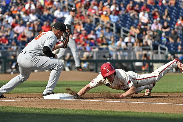 Arkansas' Heston Kjerstad, right, dives back to first base to beat Oregon State's Zak Taylorr, left, in a pick off attempt during the first inning in Game 3 of the NCAA College World Series baseball finals in Omaha, Neb., Thursday, June 28, 2018. (AP Photo/Ted Kirk)

