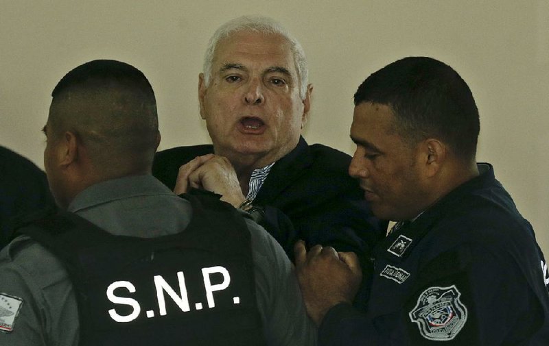 FILE — Former Panamanian President Ricardo Martinelli is escorted away in handcuffs during a recess in his hearing at the Supreme Court in Panama City, Wednesday, June 27, 2018. (AP Photo/Arnulfo Franco)