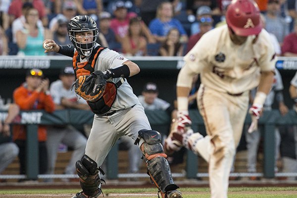Oregon State catcher Adley Rutschman throws while Arkansas' Casey Martin runs to third base during the College World Series championship game Thursday, June 28, 2018, in Omaha, Neb.