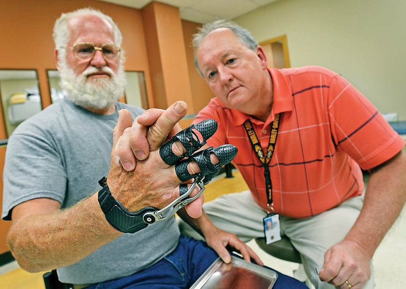 Navy veteran Fred Fuquay, left, and Steve Street, a prosthetist with the Central Arkansas Veterans Health System, observe the dexterity of Fuquay’s new articulating hand prosthetic during a fit check May 22 at the CAVHS Prosthetics Service Clinic. After Fuquay lost his middle and pinkie fingers in a workplace accident, health-system specialists provided him a custom-fit titanium and carbon-fiber device that gives him greater mobility, dexterity and hand function.