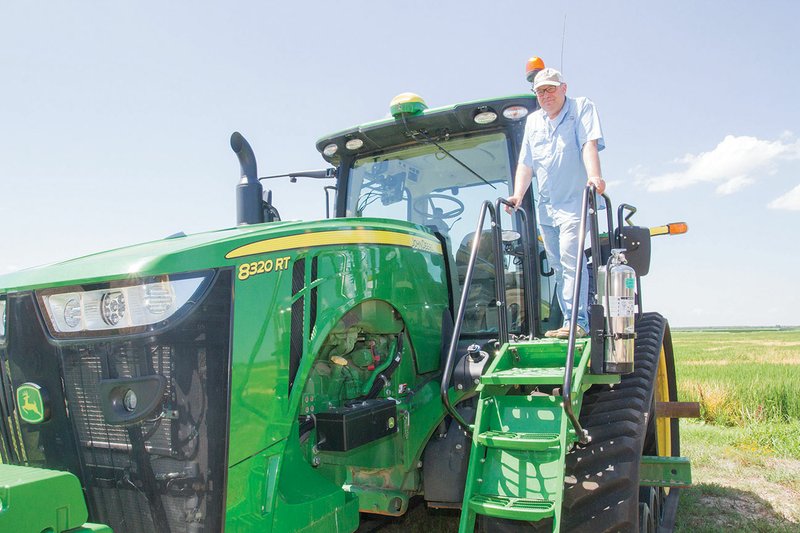 Chris Isbell of Humnoke stands on one of his John Deere tractors at his farm, Zero Grade Farms, near Humnoke. The Isbells are the 2018 Lonoke County Farm Family of the Year and the East Central District’s top farm family.