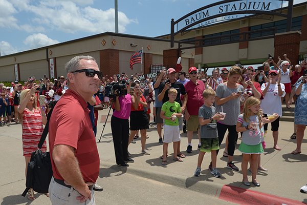 Arkansas coach Dave Van Horn smiles Friday, June 29, 2018, while watching his players and staff exit a bus as fans line the sidewalk at Baum Stadium in Fayetteville to welcome back the Razorback baseball team from its trip to the College World Series.