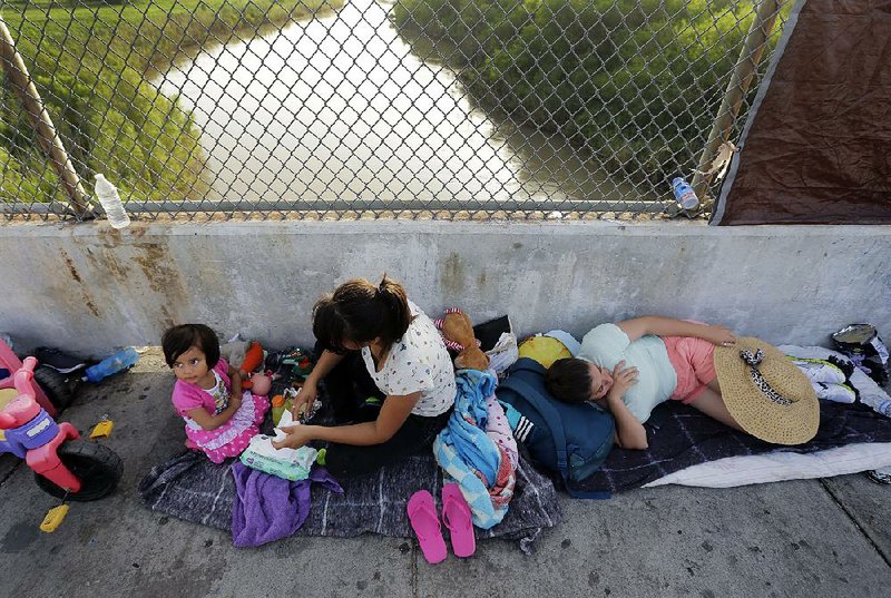People from Cuba and Guatemala seeking asylum in the United States wait Friday on the Matamoros International Bridge over the Rio Grande in Matamoros, Mexico.  