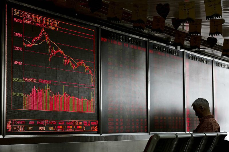 A man sits Monday in front of an electronic board displaying stock prices at a brokerage house in Beijing. China’s stock market has fallen close to levels last seen in a financial scare three years ago.  