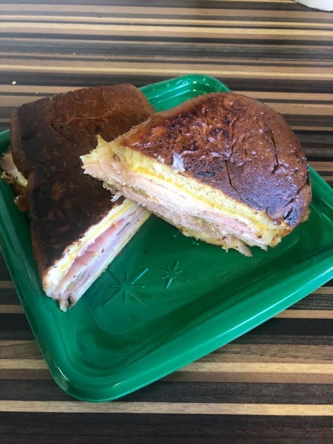 The Miami Cuban sandwich is made of ham, porchetta, swiss cheese, pickles, and mustard on homemade cuban bread and it is grilled.