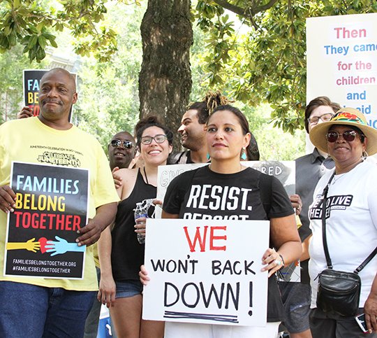 The Sentinel-Record/Rebekah Hedges PROTESTERS: Participants in a "Families Belong Together" event display handmade signs after marching down Bathhouse Row in Hot Springs National Park on Saturday. Nearly 200 people marched for two hours in 90-plus degree temperatures.