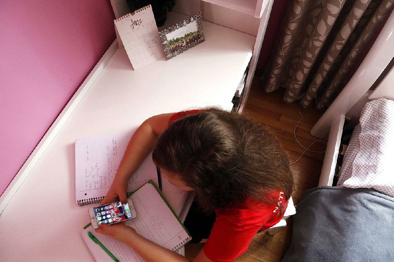 Ewelina Cudzich, 13, checks her phone in her Chicago home June 8. She understands why parents would want to monitor a phone but thinks teens should be given freedom as they prove they can be responsible. “If they’re not independent, how are they going to live in the new world?” she asks. (AP Photo/Martha Irvine)