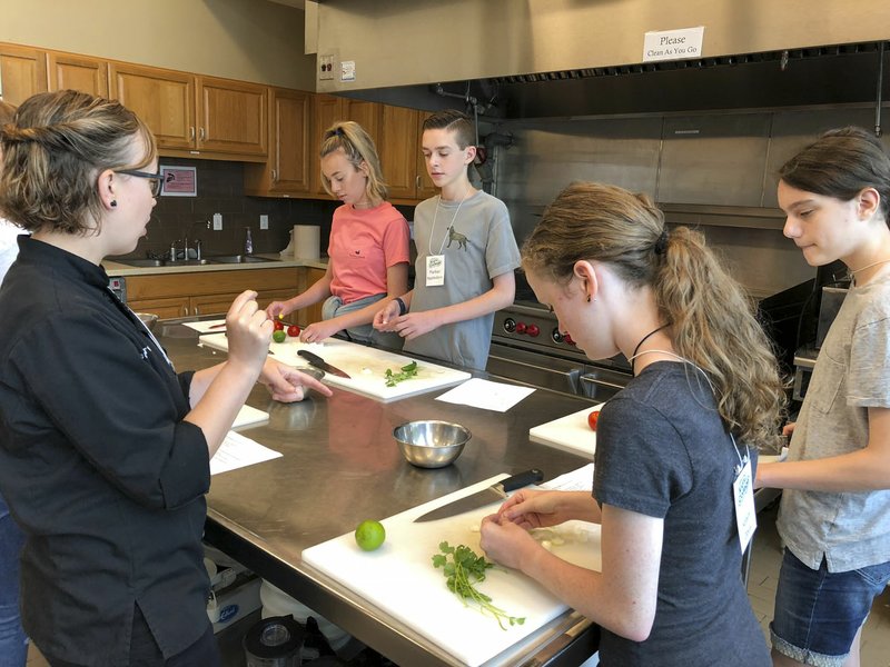Courtesy Photo/MATTIE WATSON-BAILEY Becky Miller (from left) teaches Wednesday the proper way to cut onions for a pico to Raffy Hurst, Parker Appledorn, Katyln Davis and Abby Garrett in the Tyson Foods Culinary Learning Center at Northwest Arkansas Community College in Bentonville.
