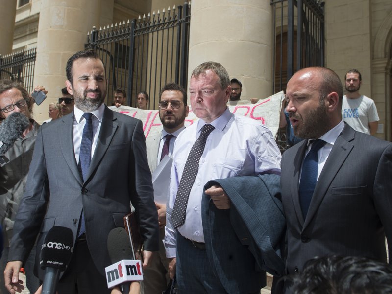 Claus-Peter Reisch, the German captain of Lifeline, a private ship that rescues migrants, is flanked by his lawyers as he leaves after an arraignment hearing in Valletta, Malta's capital, Monday, July 2, 2018. The Lifeline rescued 234 migrants in waters off Libya, then headed to Malta after Italy refused entrance to the ship. Reisch was charged with using the boat in Maltese waters without proper registration or license. (AP Photo/str)