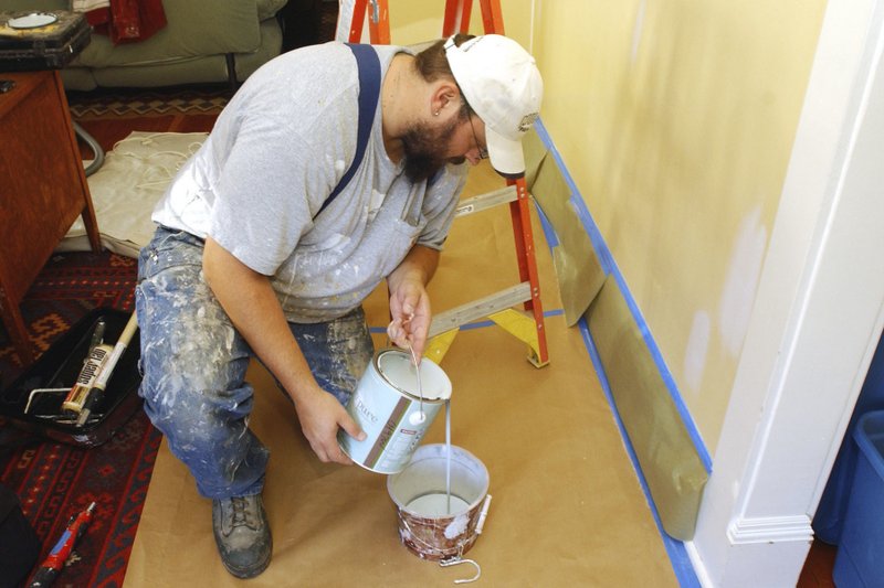 In this December 2008 file photo, painting contractor Andrew Lohr pours out the paint into a tray prior to painting his living room in Portland, Ore. Home improvements can rejuvenate a stale dwelling. A fresh coat of paint on the walls can make for a quick makeover. (AP Photo/Greg Wahl-Stephens)